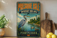 A vintage-style metal sign for Presque Isle, Pennsylvania, featuring an illustration of a heron and ducks in a lake, with a lighthouse in the background.
