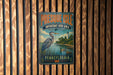 A vintage metal sign for Presque Isle, Pennsylvania, featuring an illustration of a bird and a lighthouse, mounted on a wooden fence.
