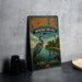 A vintage metal sign for Presque Isle, Pennsylvania, featuring an illustration of a crane and a lighthouse, is displayed on a gray countertop next to some black camera lenses.