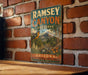 A vintage metal sign for Ramsey Canyon Preserve, featuring a bird and a mountain landscape, is displayed on a brick wall.