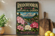 A vintage-style sign for the Rhododendron Species Botanical Garden in Washington, featuring a scenic landscape with a mountain and flowers.