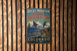 A vintage-style metal sign for Rocky Mountain Bird Observatory in Colorado, featuring a blue bird and a mountainous landscape.