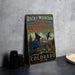 A vintage-style metal sign for the Rocky Mountain Bird Observatory in Colorado, featuring an illustration of a blue bird and a mountainous landscape.