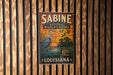 A vintage-style metal sign for the Sabine National Wildlife Refuge in Louisiana, featuring an illustration of a heron and a sunset landscape.