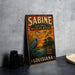 A vintage-style metal sign for Sabine National Wildlife Refuge in Louisiana, featuring an illustration of a crane and birds in flight against a sunset landscape.