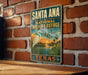 A vintage-style metal sign for the Santa Ana National Wildlife Refuge in Texas, featuring an illustration of a bird, cactus, and sunset.