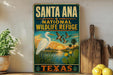 A vintage-style sign for Santa Ana National Wildlife Refuge in Texas, featuring an illustration of a white egret, ducks, and a sunset landscape.