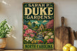A vintage-style metal sign for "Sara P. Duke Gardens" in North Carolina, featuring a garden scene with flowers and a building.