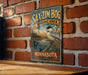 A vintage metal sign for the Sax-Zim Bog Birding Area in Minnesota, featuring a black and white chick perched on a branch against a scenic background.