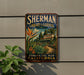 A vintage-style sign for the Sherman Library & Gardens in Corona, California, featuring a tropical garden scene with palm trees and colorful flowers.