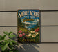 A vintage-style metal sign for Shore Acres State Park Garden in Oregon, featuring a scenic landscape with flowers and greenery.