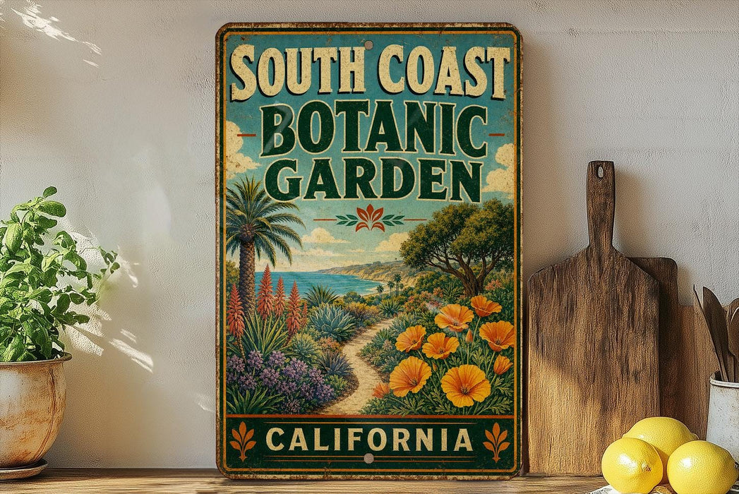 A vintage-style metal sign for the South Coast Botanic Garden in California, featuring a tropical garden scene with palm trees, flowers, and a path leading to the garden.