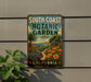 A vintage-style metal sign for the South Coast Botanic Garden in California, featuring a tropical garden scene with palm trees, flowers, and a winding path.