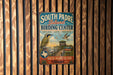 A vintage-style metal sign for the South Padre Island Birding Center, featuring a bird illustration and text promoting birdwatching and conservation.
