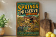A vintage-style poster advertising Springs Preserve, Nevada, featuring a scenic landscape with a building and a waterfall.