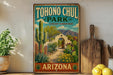 A vintage-style metal sign for Tohono Chul Park, featuring a desert garden oasis with cacti, succulents, and a wooden archway entrance.