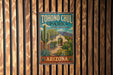 A vintage-style metal sign for Tohono Chul Park, featuring a desert garden and cacti, is displayed on a wooden wall.