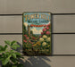 A vintage-style metal sign for Tower Hill Botanic Garden in Boston, Massachusetts, featuring a lush garden scene with flowers and a tower.