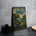 A vintage-style metal sign for "Wave Hill New York" featuring a garden scene with a house and flowers, placed on a gray countertop next to some black camera lenses.