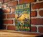 A vintage-style metal sign for Wheeler National Wildlife Refuge in Alabama, featuring a duck and a crane in flight against a sunset backdrop.