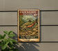 A vintage-style postage stamp featuring a chum salmon fish, mounted on a wall next to a plant.