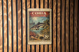 A metal sign with a fish illustration and text, mounted on a wooden wall.