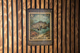 A metal plate with a postage stamp design featuring a fish, mounted on a wooden wall.
