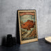 A vintage-style stamp depicting a large fish, likely a Red Grouper, is displayed on a surface next to some black camera lenses.