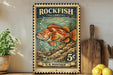 A vintage-style postage stamp featuring a colorful illustration of a rockfish, with the text "ROCKFISH (YELLOWEYE)" and "U.S. POSTAGE" printed on it. The stamp is displayed on a shelf next to a wooden cutting board and a potted plant.