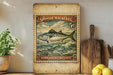a Spanish mackerel stamp with a fish illustration, placed on a wooden surface next to a wooden cutting board and some lemons.