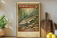 A vintage postage stamp featuring a fish, likely a sturgeon, is displayed on a shelf next to a wooden cutting board and some lemons.