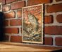 a framed illustration of a fish, likely a Tarpon, against a brick wall background.