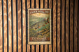 A vintage U.S. postage stamp featuring a tiger musky fish, hanging on a wooden wall.
