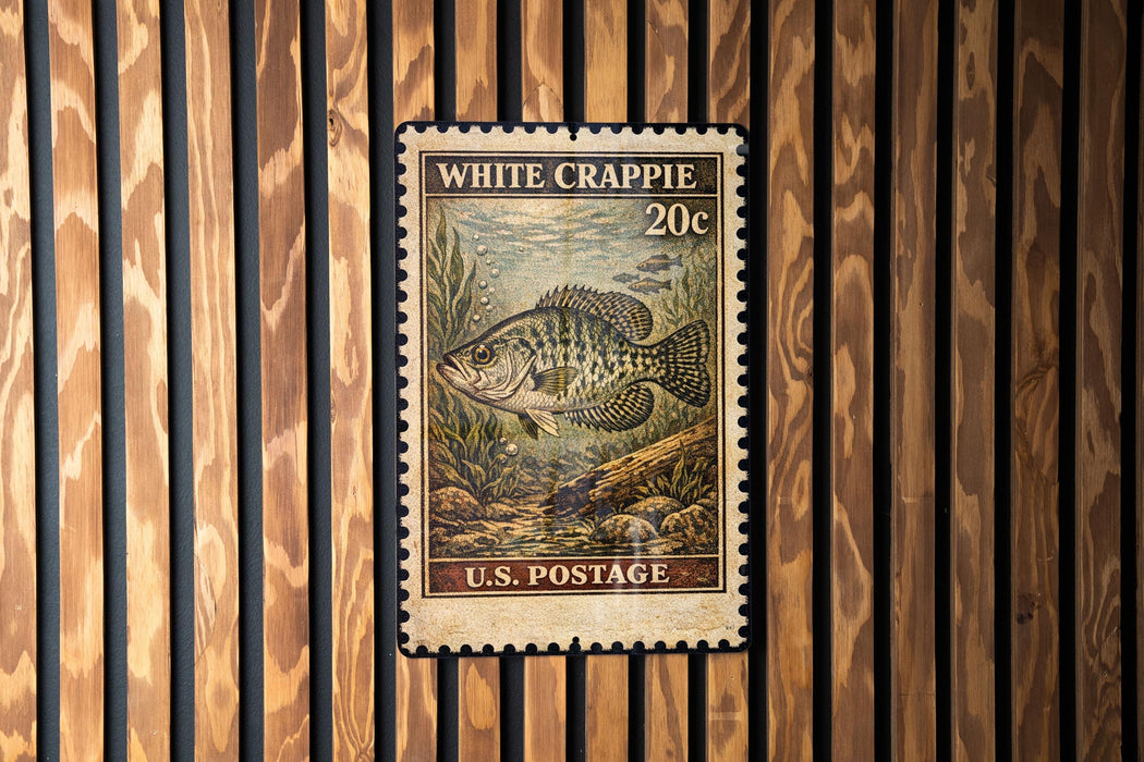 A U.S. postage stamp featuring a fish, specifically a White Crappie, is displayed on a wooden wall.
