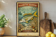 A vintage-style postage stamp featuring a yellowtail snapper fish, with a price of 10 cents, is displayed on a wooden surface next to a wooden cutting board and a potted plant.