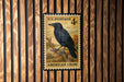 A U.S. postage stamp featuring an American crow perched on a branch.