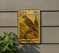 A postage stamp featuring an illustration of an American Kestrel bird, a type of bird of prey, perched on a branch.
