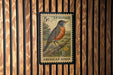 A U.S. postage stamp featuring an illustration of an American robin perched on a branch.