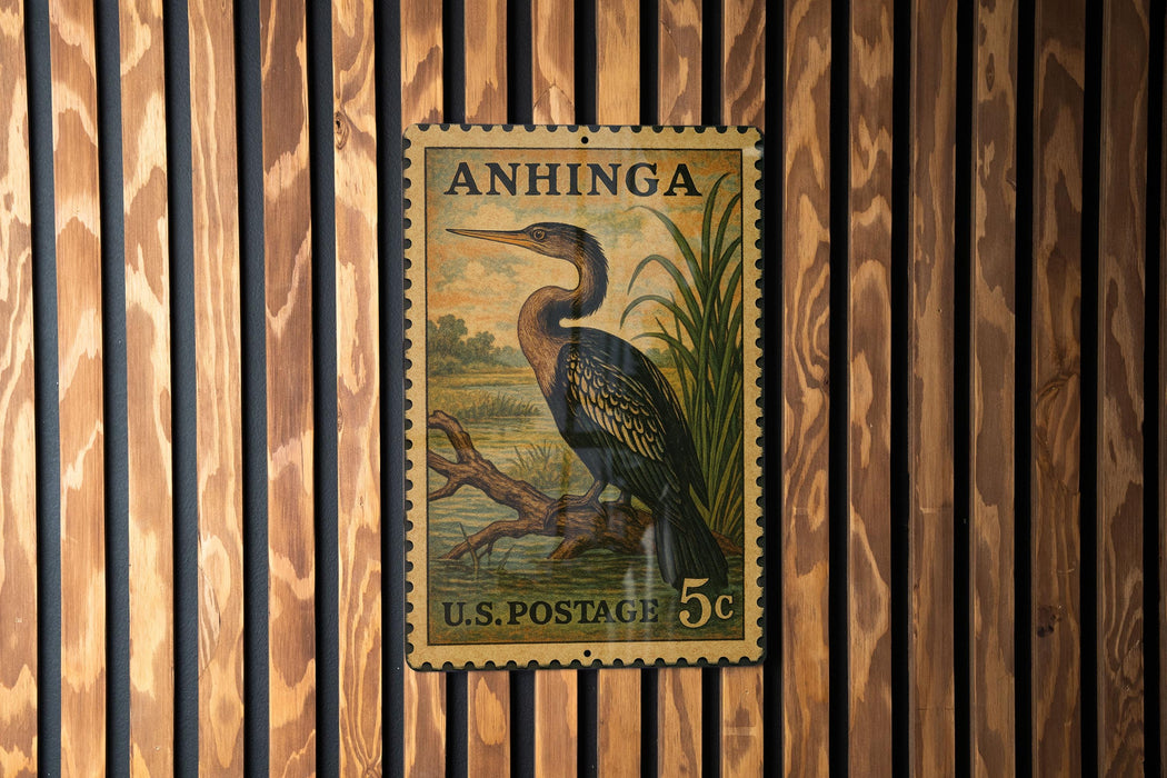 A vintage U.S. postage stamp featuring a large bird, likely a heron, perched on a branch. The stamp is mounted on a wooden wall with vertical slats.