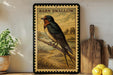 A framed illustration of a barn swallow perched on a branch, with a rural landscape in the background.