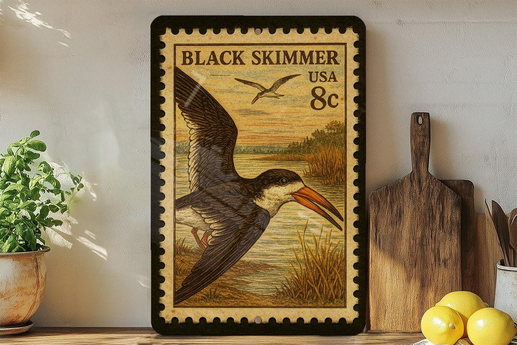 A framed postage stamp depicting a black skimmer bird is displayed on a shelf next to a wooden cutting board and a potted plant.