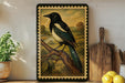 A framed painting of a black and white bird perched on a branch is displayed on a shelf, accompanied by a wooden cutting board, a potted plant, and a bowl of lemons.