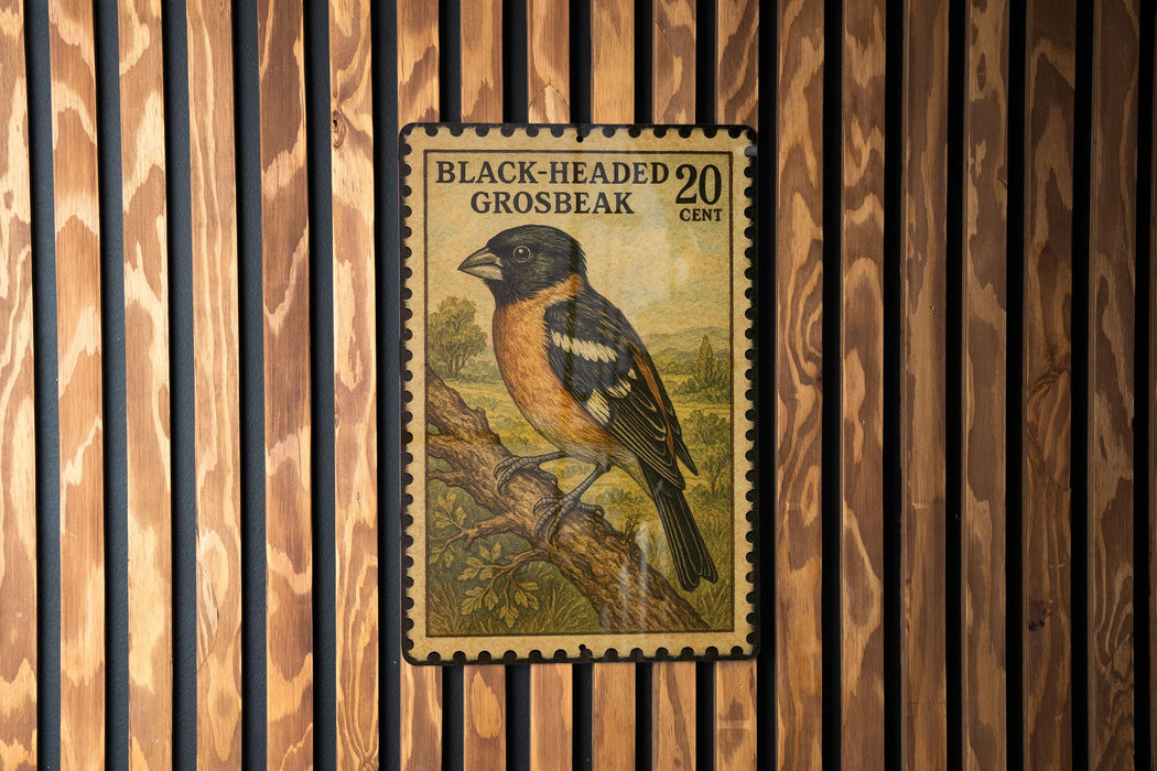 A postage stamp featuring a black-headed grosbeak, a type of bird, is displayed on a wooden wall.