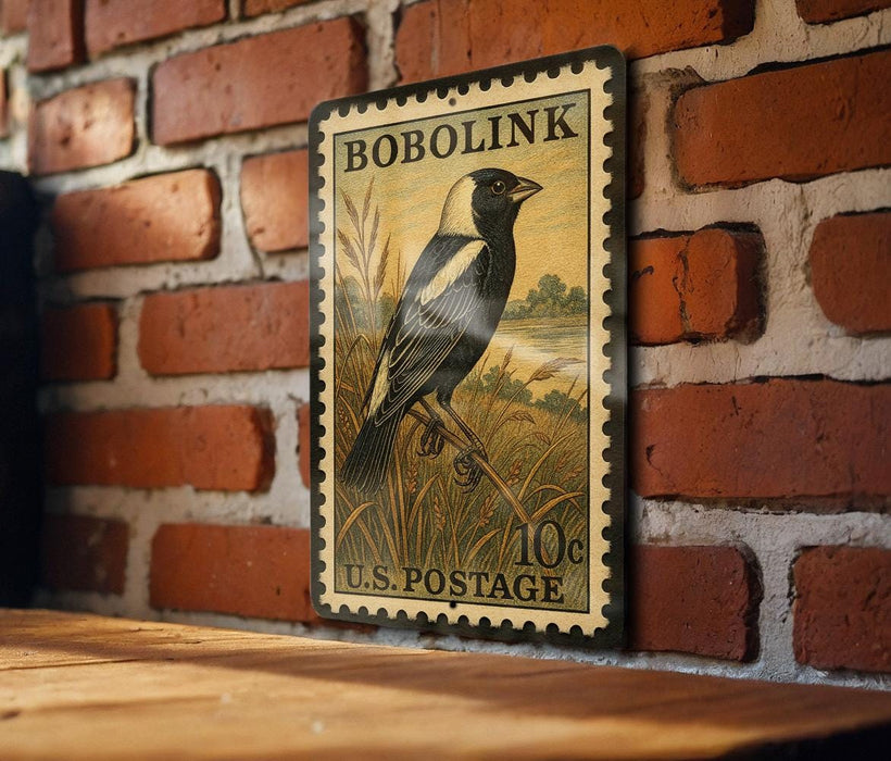 A vintage-style postage stamp featuring a black and white bird perched on a grassy field, mounted on a brick wall.