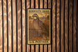 A vintage Bobwhite Quail postage stamp is displayed on a wooden wall.