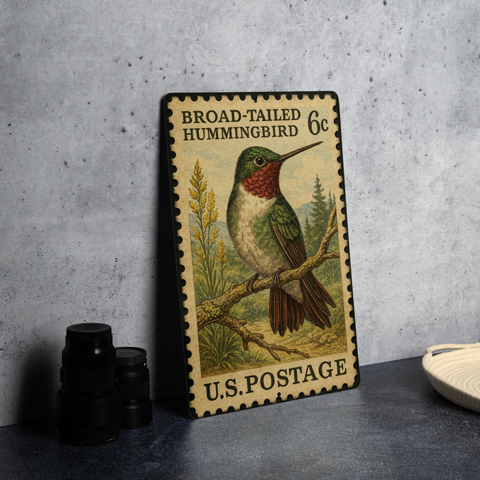 A vintage postage stamp featuring a colorful illustration of a broad-tailed hummingbird, sitting on a branch.