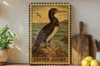 a framed illustration of a brown booby bird, which is perched on a rock near the ocean. The framed artwork is displayed on a shelf, surrounded by various kitchen utensils and decorative items.