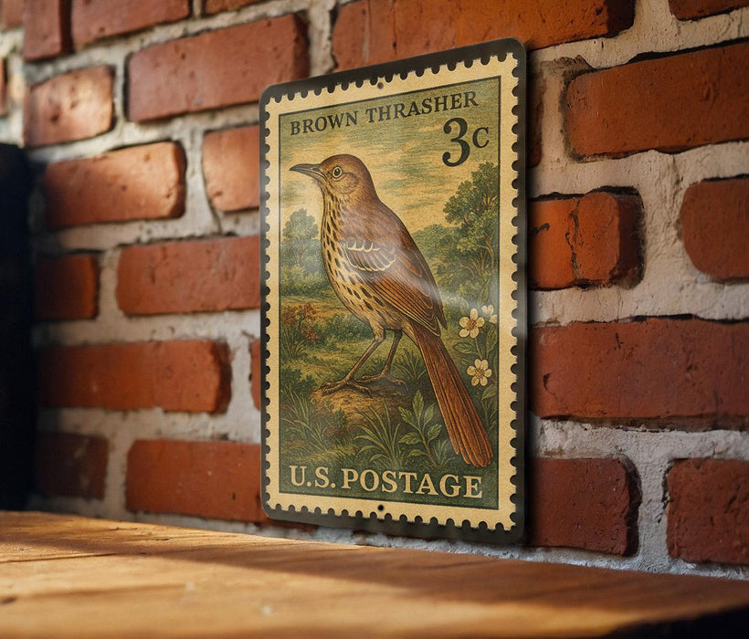 A vintage brown thrasher postage stamp is displayed on a brick wall, featuring a detailed illustration of a bird perched on a branch.