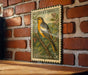 A vintage U.S. postage stamp featuring a colorful illustration of a bird perched on a branch, mounted on a brick wall.