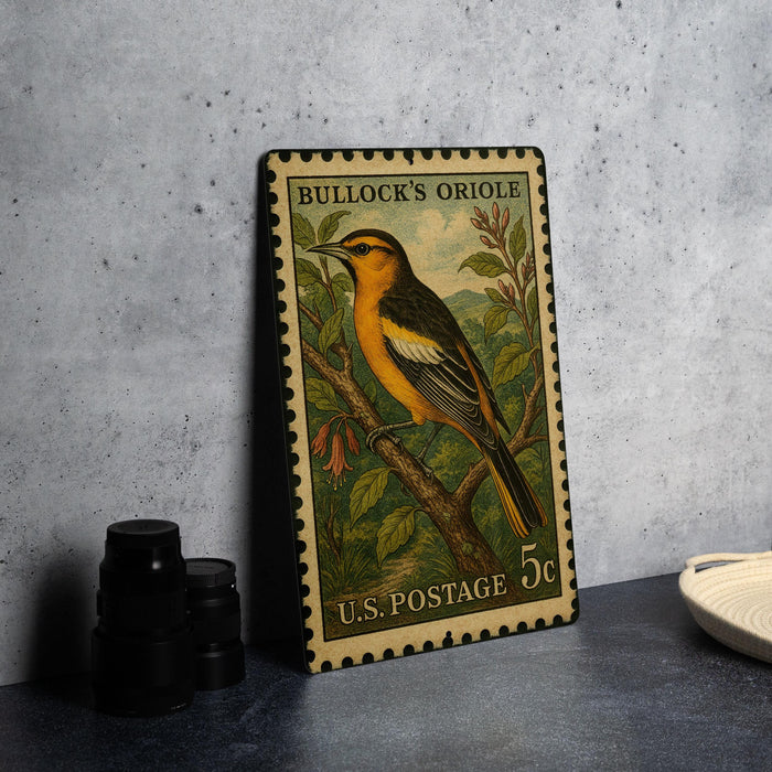 A metal stamp depicting a bullock's oriole, a type of bird, is displayed on a table.